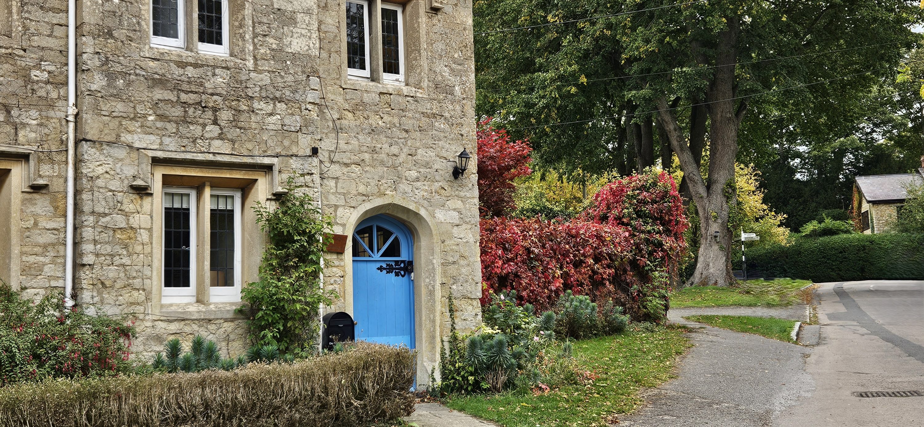 Old school house with blue door by village green